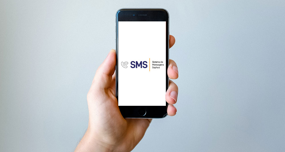 Mão segurando aparelho celular mostrando apenas o logotipo do serviço SMS