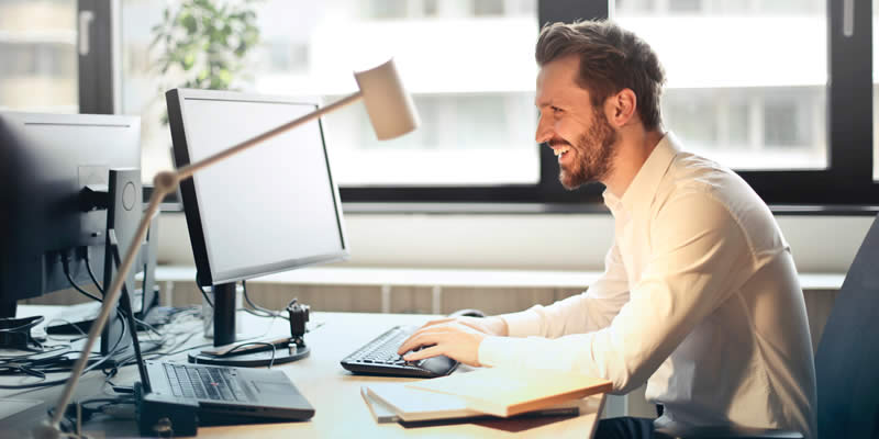 Homem em mesa iluminada usando computador