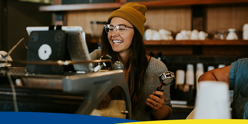 Mulher sorrindo utilizando uma máquina de café