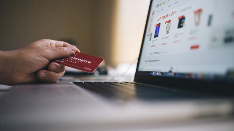 Pesquisa mostra impacto das tecnologias no consumo Mão segurando cartão de crédito em frente a um notebook