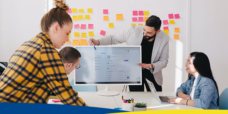 Pessoas planejando em uma mesa de escritório, com post-its ao fundo