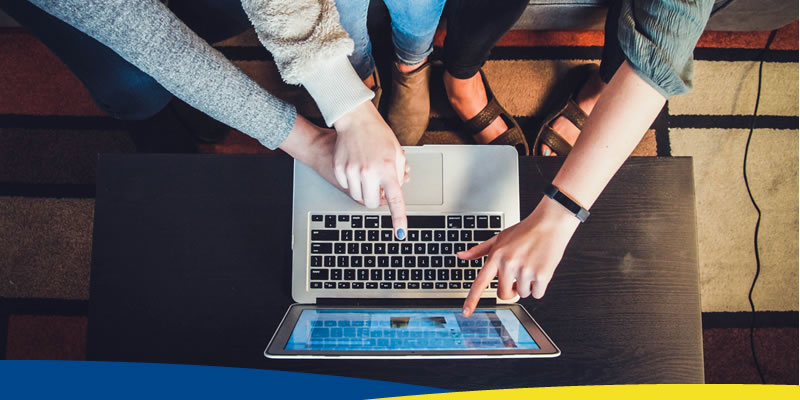 Mãos apontando tela de notebook em cima de uma mesa