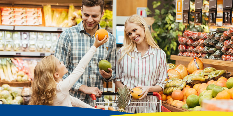 Família sorrindo com um carrinho de supermercado
